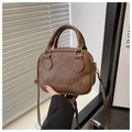 Detail of vintage brown leather shell bag featuring embossed logo and cylinder handles - Coffee