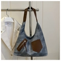 Detail of vintage canvas tote with brown leather accents hanging on a clothing rack - Blue