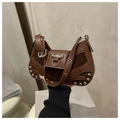 Dark brown leather shoulder bag with rivets and mixed textures shown on a pedestal - Brown