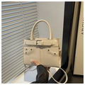 Detail of creamy white leather handbag featuring silver buckle and litchi grain texture - White