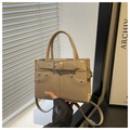 Detail of beige faux leather handbag with decorative buckle and silver rivets shown in hand - Khaki