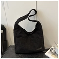 Detalle de bolso tote negro de pana con bolsillo delantero y placa dorada de fashion - Negro