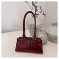 Detailed view of the dark red leather shoulder bag with decorative belt and silver buckle - Burgundy