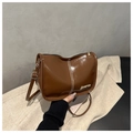 Détail d'un sac à bandoulière en cuir brillant marron avec coutures blanches et logo doré - Marron