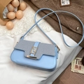 Light blue saddle shoulder bag with woven textured flap and golden geometric buckle - Blue