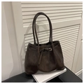 Detailed close-up of dark brown leather tote bag with gold buckle on white books - No Pendant / Coffee