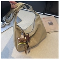 Detalle de bolso de media luna beige con costuras blancas y accesorio de amuleto de osito - Con Colgante / Caqui