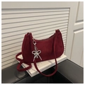 Detail of burgundy suede shoulder bag with silver bow heart pendant on a book - Red with Pendant