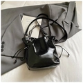 Détail d'un sac seau noir brillant avec poignée en chaîne sur un tissu de fond blanc - Noir Sans Pendentif