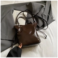 Détail du sac seau marron foncé brillant avec chaîne métallique et cordon sur tissu - Café Sans Pendentif