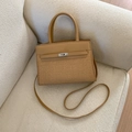 Straw and leather patchwork handbag with silver metal turn-lock on a beige sofa - Khaki (No Pendant)