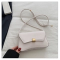 Detailed view of cream baguette bag featuring a sleek gold rectangular twist lock - White