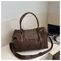 Macro shot of dark coffee large travel bag showing pleated texture and leather handle - Brown