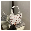 Detail of white cherry print bucket bag showing PU leather texture and stylish knot handle - White