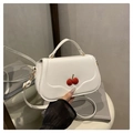 Detail view of a white crossbody bag featuring 3D red cherry accents and matte finish - White