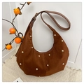 Detail of caramel suede crescent hobo bag featuring golden rivet studs on wooden background - Brown