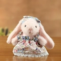 Peluche di coniglio rosa con vestito a fiori e bordo in pizzo in ambiente accogliente - 10cm / Rosa