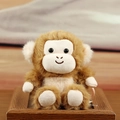 Cute brown and beige plush monkey doll pendant sitting on a dark wooden frame base - Monkey