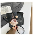 Detail der schwarzen geflochtenen Umhängetasche mit Holzschnalle und Plüschbär-Anhänger - Mit Anhänger / Schwarz