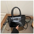 Detalle del bolso negro brillante con asas cilíndricas y diseño de hebilla decorativa - Negro
