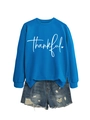 Detail of blue crewneck sweatshirt featuring white Thankful script and heart print - Lake Blue (White Font)