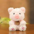 Plush pink pig doll in sitting pose with soft fur and brown brand tag on wood surface - Sitting Posture / Pink Pig