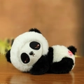 Cute lazy panda plush toy in black and white fur, lying down on a cozy wooden table - Panda