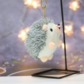 Detailed close-up of a plush hedgehog keychain hanging on a metal display stand - Height about 11 / Army Green
