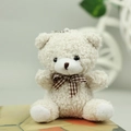 Dettaglio dell'orsetto di peluche color crema con pelliccia riccia e fiocco a quadri - Altezza circa 10cm / Bianco Sporco