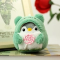 Ciondolo pinguino di peluche con felpa orso verde e lecca-lecca su sfondo di legno - Verde / 10cm