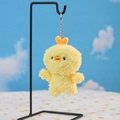 Close-up of a soft yellow plush chicken keychain with a heart detail on a metal stand - Chicken