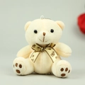 Detailed macro view of beige plush teddy bear pendant with metal ball chain and brown bow - 10cm / Beige
