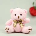 Detail of pink plush teddy bear pendant with golden bow and soft fluffy texture - 10cm / Pink