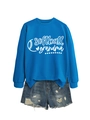 Flat lay of a blue softball grandma sweatshirt paired with distressed denim shorts - Lake Blue (White Font)