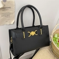 Classic black leather vintage handbag with golden heart buckle on a woven chair - Black