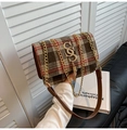 Detail of red and brown plaid crossbody bag with golden S-buckle and tassel accent - Brown