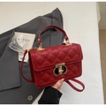 Detail of red quilted handbag with gold T-lock and leather texture in a stylish setting - Burgundy