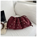 Bolso saco vintage de ante burdeos con tachuelas doradas en un sofá blanco - Rojo