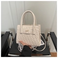 Sac bandoulière en similicuir crème avec texture matelassée et nœud doré sur chaise - Blanc