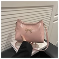 Detailed view of pink bow decoration on glossy shoulder bag with golden metallic hardware - Pink