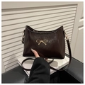Detail of dark brown patent leather shoulder bag with gold bow ornament and glossy finish - Brown