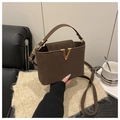 Détail d'un sac seau en cuir marron avec boucle en V dorée et texture en daim élégante - Marron
