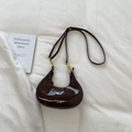 Close-up of dark brown patent leather hobo bag with gold hardware and logo detail - Brown