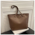 Detail of a dark brown matte leather tote bag with gold logo plate and metal rings - Brown