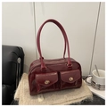 Dettaglio di una borsa a spalla in pelle cerata rosso scuro con due tasche e chiusure oro - Rosso