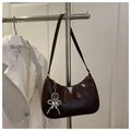 Detail der dunkelbraunen Lackledertasche mit silbernen Schmetterlings- und Herzanhängern - Braun
