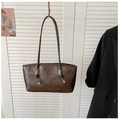 Detalle de bolso tote en cuero marrón oscuro con grabado de letras y hebillas metálicas - Marrón