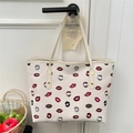 Off-white tote bag with colorful lipstick prints and leather handles hanging on a door - Off White
