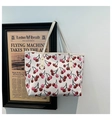 Detail of white tote bag with cherry print, litchi texture, and metal rivets - White