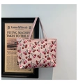 Detailed view of pink cherry print tote bag with golden rivets hanging on a frame - Pink